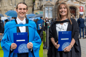 Two people in graduation gowns, one blue for PhD and one black for MA, holding their degree folders
