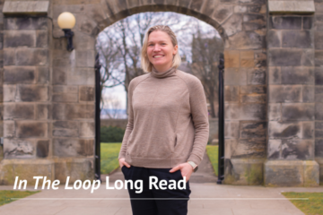 A smiling woman stands in front of an archway